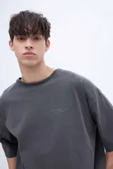 Remera de algodón con calce oversize y textura suave. Presenta un diseño de cuello redondo, mangas cortas con bordado detallado en una de ellas y un acabado de tela lavada.