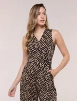 Enterito cropped con caída fluida, sin mangas y con escote en V cruzado estilo wrap. Presenta un lazo lateral para anudar en la cintura, bolsillos prácticos y pantalón midi de corte amplio con diseño geométrico en tonos negro y beige.