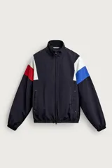 Chaqueta técnica relaxed fit de color negro, con cuello alto, cierre frontal de cremallera bidireccional y bolsillos de vivo. Presenta diseño color block en las mangas con inserciones en blanco, rojo y azul.