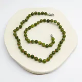 Collar de cuentas de jade verde de 6mm con separadores de hilo naranja y cierre de mosquetón de acero hipoalergénico.