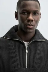 Jersey negro de punto perlado con cuello perkins y cierre frontal de cremallera.