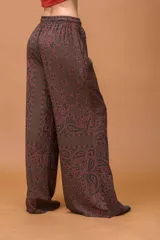 Pantalón palazzo de tiro medio con cintura elástica y cordón ajustable. Presenta un diseño de corte amplio y fluido con un estampado de motivos paisley en tonos marrones y azul oscuro.