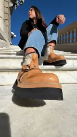 Botas cortas de cuero en color tostado y blanco con textura animal print de cocodrilo, suela de plataforma plana y robusta en color negro, y detalle de argolla metálica lateral.