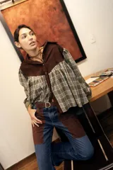 Camisa oversize confeccionada en pana marrón oscuro en la parte superior y tejido a cuadros en tonos verde y blanco en la parte inferior, con mangas largas abullonadas y cierre frontal de botones.