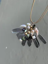 Collar con dije de metal plateado con forma de hojas y adornos de perlas y piedras de colores.