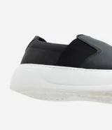 Championes tipo slip-on confeccionadas en cuero napa color negro, con elásticos laterales para un ajuste cómodo y suela robusta de goma en color blanco.