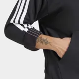Canguro deportivo Adidas de felpa francesa color negro, con capucha ajustable, bolsillo frontal tipo canguro y las icónicas tres tiras blancas en las mangas. Cuenta con el logo de la marca bordado en el pecho.