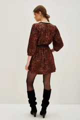 Vestido corto de estilo camisero con estampado animal print en tonos caramelo y negro. Presenta cuello en V con solapas negras, mangas tres cuartos y un lazo negro ajustable en la cintura para entallar la silueta.