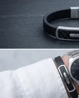 Pulsera masculina con banda de goma negra con textura de fibra de carbono y placa central de acero inoxidable.