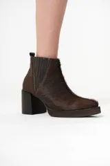 Botas Chelsea de cuero con pelo color marrón oscuro, con elásticos laterales y cierre interno. Taco bloque de madera y plataforma delantera.