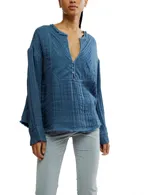 Camisa azul de gasa de algodón con cuello en V, mangas largas y botones.