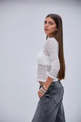 Remera blanca de encaje con diseño texturizado, cuello alto y mangas largas.