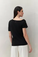 Top tejido color crudo, de silueta ajustada con diseño minimalista y escote redondo, adornado con pequeños botones metálicos.