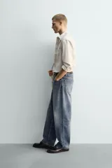 Camisa de corte relajado confeccionada en tejido de algodón con estampado de cuadros difuminados. Presenta cuello solapa, manga larga con puños abotonados, bolsillo de plastrón en el pecho y cierre frontal de botones.