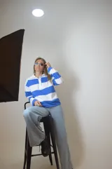 Sweater de punto a rayas horizontales azules y blancas, con cuello polo y cierre parcial con cremallera.