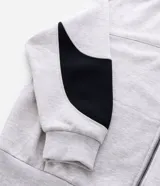 Buzo con capucha y cierre frontal, confeccionado en tejido fleece de algodón y poliéster. Presenta un diseño bicolor con cuerpo en gris melange y paneles laterales en las mangas de color negro, bolsillos frontales, y puños y ruedo en rib.