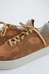 Zapatillas de gamuza verde oliva con cordones marrones y suela de goma color crema.