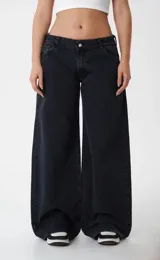Pantalón de jean estilo wide leg, de tiro bajo y corte holgado, en color negro lavado.