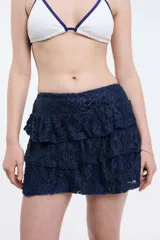 Short pollera de encaje azul marino con diseño de volados escalonados. Presenta una silueta femenina y delicada con forro interior.