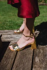 Sandalias doradas con taco bloque de 5 cm y capellada combinada en dorado y negro.