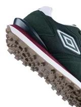 Championes urbanos Umbro de diseño deportivo, confeccionados en una combinación de gamuza y malla en tonos beige y gris claro. Presentan el logo de la marca en el lateral, una entresuela blanca con refuerzo azul oscuro en el talón y una suela dentada en color marrón.