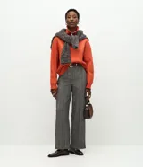 Pantalón de vestir de corte recto y tiro alto, confeccionado en tejido gris con textura tipo espiga. Presenta un diseño clásico con cierre frontal y trabillas para cinturón.