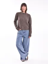 Cárdigan tejido color gris claro con diseño trenzado, cuello redondo y cierre frontal con botones marrones.