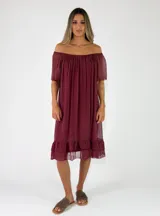 Vestido midi bordó de viscosa, con escote off-shoulder fruncido, mangas cortas y detalle de volados en el ruedo.