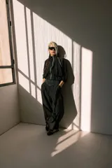 Campera negra de tela sintética con cierre frontal, cuello alto, mangas 3/4 con puños elásticos y cintura ajustable con cordón.