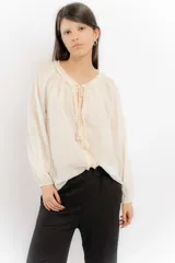 Blusa celeste de algodón con escote en V con lazos y mangas largas abullonadas con puños elásticos.