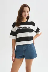 Remera cropped de algodón con diseño de rayas horizontales en blanco y negro, cuello redondo y manga corta. Cuenta con un estampado con la inscripción "REVOLUTION" en el pecho.
