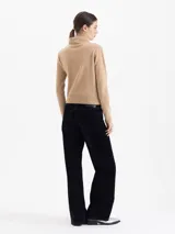 Sweater de lana merino color negro, con cuello medio alto y detalle de frunces en los hombros que aportan volumen. De calce regular y tejido suave.
