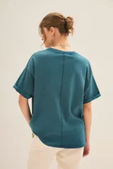 Remera oversize de jersey de algodón color verde azulado con lavado stonewash. Presenta una estampa frontal de inspiración deportiva con la palabra "ROCK" y el número "26" en foil dorado.