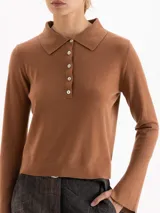 Sweater de punto color rosa, con cuello polo, cierre frontal con botones y mangas largas con puños acampanados.