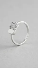 Anillo de plata 925 con diseño geométrico rectangular y detalle de acrílico blanco con vetas negras.