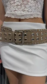 Cinturón marrón con hebilla metálica plateada y doble hilera de ojalillos metálicos.