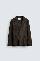 Blazer de corte relajado confeccionada en piel con acabado de ante. Presenta cuello con solapas de muesca, cierre frontal de dos botones, mangas largas y bolsillos de plastrón en la cadera. El diseño no posee forro interior y cuenta con aberturas en la parte trasera.