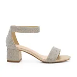 Sandalia de fiesta con taco cuadrado bajo, confeccionada en material plateado con acabado brillante. Presenta una tira frontal ancha y una pulsera al tobillo, ambas completamente cubiertas de strass.