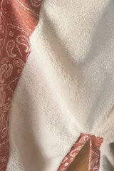 Kimono de jean con estampado tipo bandana en tonos rojizos y anaranjados, con forro interior de corderito blanco. Presenta un diseño de corte recto, mangas largas y cinturón del mismo tejido.