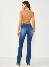 Jean de mezclilla azul oscuro con efecto lavado y sutil desgaste, de corte recto o ligeramente acampanado (bootcut).