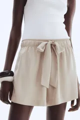 Short de sarga de tiro alto, color beige, con corte holgado, cintura elástica y lazo decorativo frontal. Cuenta con bolsillos laterales discretos.