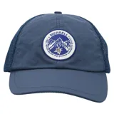 Gorra tipo trucker color azul, con panel frontal y visera de tela técnica, y paneles laterales y traseros de malla transpirable. Presenta un parche circular bordado en el frente con el logo de Merrell y un diseño de montaña.
