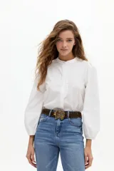 Camisa de algodón color blanco, con cuello mao, cierre frontal oculto y detalle de volado vertical. Presenta mangas largas abullonadas con puños elásticos.