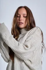 Sweater color crema con cuello alto y diseño de trenzas.