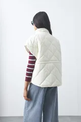 Chaleco acolchado de nylon con diseño capitoneado, cuello alto y cierre frontal con botones a presión. Presenta un calce amplio y versátil.