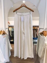 Pantalón de lino color beige, de corte amplio y fluido, con cintura elástica fruncida y cordón ajustable.