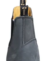 Bota tipo Chelsea de cuero color gris oscuro, con elásticos laterales negros y suela de goma dentada. Presenta tiradores en la parte superior para facilitar el calce.