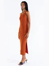 Vestido midi sin mangas confeccionado en punto jersey de tejido italiano con hilo Lurex en dos colores que aporta brillo sutil. Presenta escote bote redondeado y aberturas laterales.