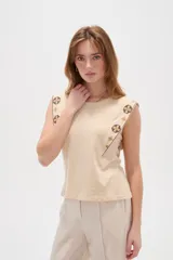 Remera negra de algodón con cuello redondo, corte al cuerpo y detalles de bordado geométrico multicolor en los hombros y sisas.