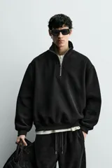Sudadera de corte relajado confeccionada en pana con interior de tejido polar. Presenta cuello subido con cierre frontal de cremallera, manga larga y acabados en rib. Incluye bajo ajustable con cremalleras laterales.